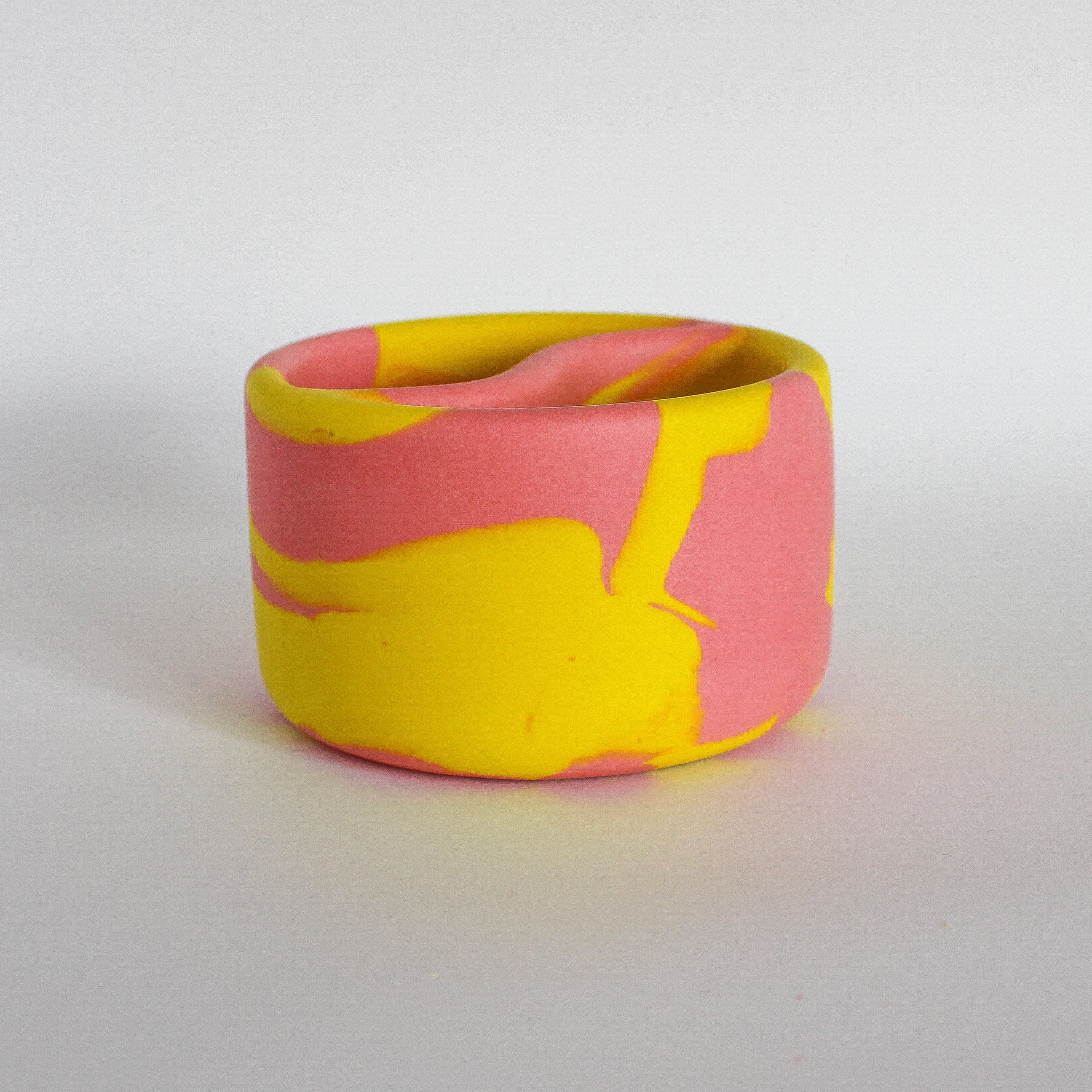 Front view of a handmade decorative bowl with a marbled pink and yellow pattern, shaped like a Yin Yang symbol with two compartments.